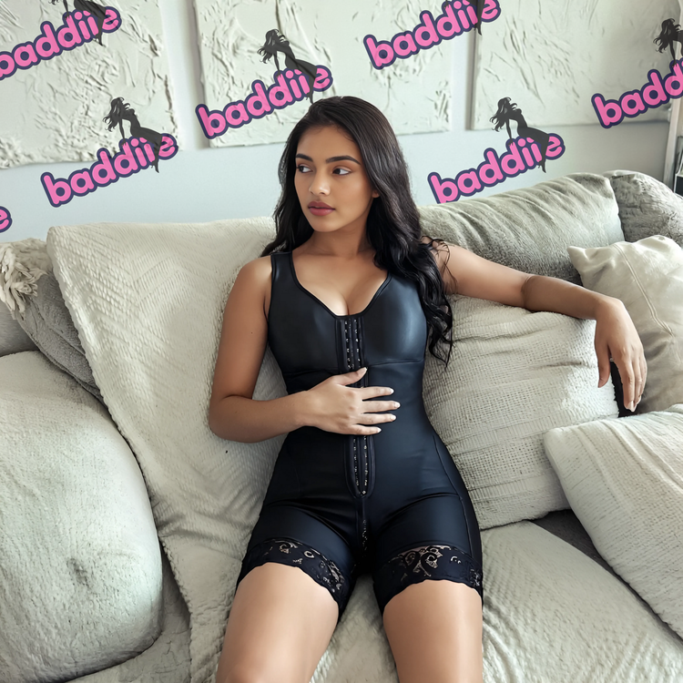 Woman wearing a black shapewear outfit sitting on a couch with 'baddiie' branding in the background.